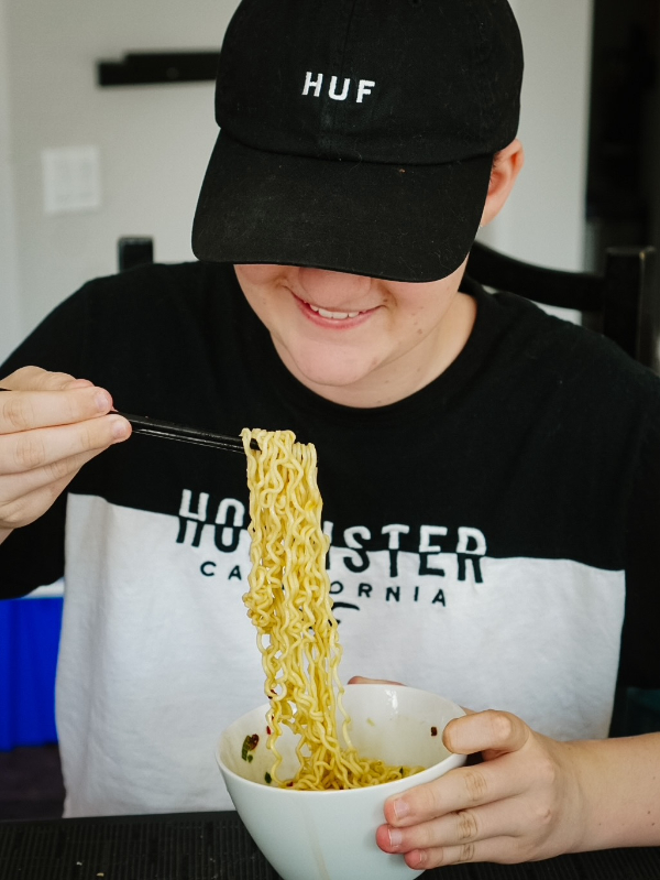 Teenager eating ramen noodles